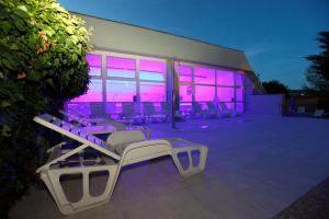 a group of chairs sitting outside of a building with purple lights at MÁJ Hotel Medical Wellness in Piešťany