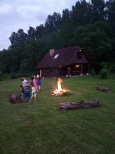 un grupo de personas de pie alrededor de un fuego delante de un granero en Guest Home "Būriņi", en Baldone