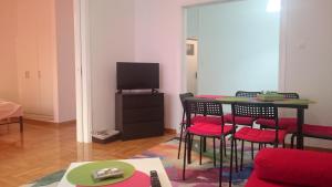 ein Wohnzimmer mit einem Tisch, Stühlen und einem TV in der Unterkunft Bozena Apartment in Athen