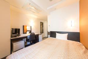 a bedroom with a bed and a desk with a computer at Sanco Inn Nagoya Fushimi in Nagoya