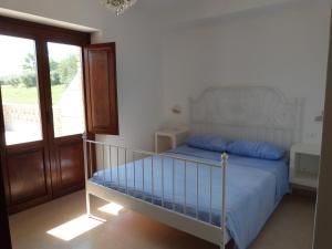 a bedroom with a bed with blue sheets and a balcony at Country House 3Quatrì in Corropoli