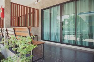 balcón con banco de madera y grandes ventanas de cristal en Nam Sai Loft Resort, en Chao Lao Beach