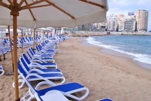 a row of beach chairs sitting on top of a beach at Tolip Hotel Alexandria in Alexandria