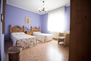 a bedroom with two beds and a chair and a window at Maria la Carbayeda in Luanco