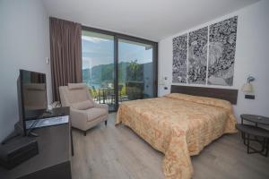 1 dormitorio con 1 cama, 1 silla y TV en B&B Vista Lago en Como