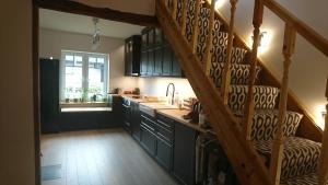 a kitchen with black cabinets and a wooden staircase at White House Pärnu in Pärnu