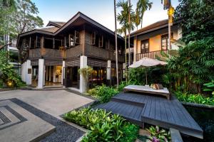 Casa con terraza de madera con banco y sombrilla en Rarin Jinda Wellness Spa Resort en Chiang Mai