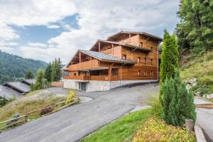 a large wooden house on a hill with a driveway at Les Terrasses De Perrières in Les Gets