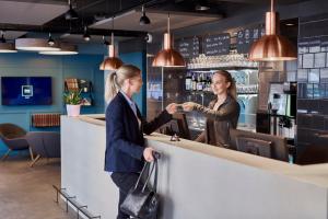 zwei Frauen, die Hände schütteln an einer Bar in der Unterkunft Zleep Hotel Copenhagen City in Kopenhagen