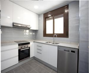 a kitchen with white cabinets and a sink and a window at Apartamentos Ocea in Cambrils