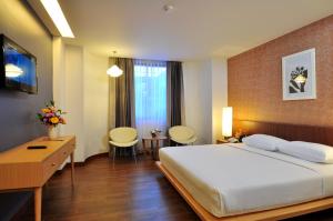 a bedroom with a large bed and a desk and chairs at Flipper Lodge Hotel - SHA Extra Plus in Pattaya