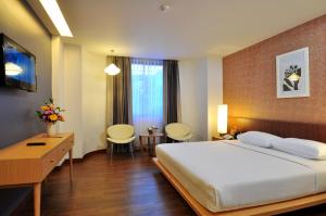 a bedroom with a large bed and a desk and chairs at Flipper Lodge Hotel - SHA Extra Plus in Pattaya Central