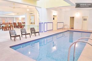 uma grande piscina com cadeiras e uma mesa num edifício em Rani Mahal Hotel em Jaipur