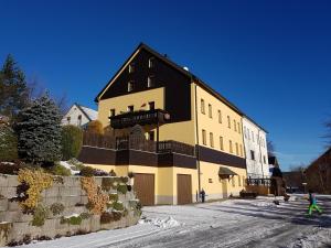 a large yellow and black building on a snowy street at Ferienwohnungen "Am Schlössel" in Kurort Oberwiesenthal