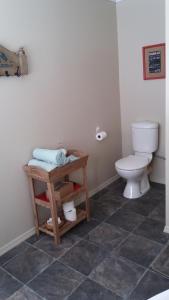 a bathroom with a toilet and a table with towels at Little Red School House in Oamaru