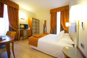 ein Hotelzimmer mit einem großen Bett und einem Tisch in der Unterkunft Best Western Crystal Palace Hotel in Turin