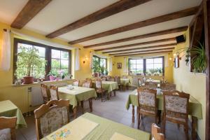 un restaurante con mesas, sillas y ventanas en Pension Deichgraf Middelhagen, en Middelhagen