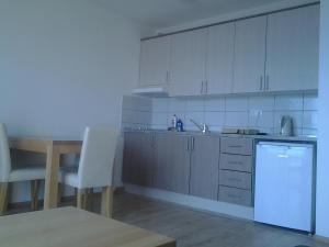 a kitchen with white cabinets and a table and a dishwasher at Apartmani "Grgic" in Omiš