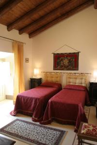 アチレアーレにあるB&B Palazzo Gambinoのベッドルーム1室(赤いシーツと絵画が飾られたベッド2台付)