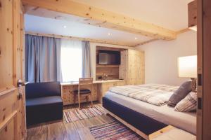 Schlafzimmer mit einem Bett und einem Schreibtisch mit einem TV in der Unterkunft Raderhof in Feld am See