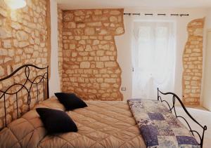 a bed in a bedroom with a stone wall at Casa Vacanze L'arco di Fondarca n.16 in Cagli