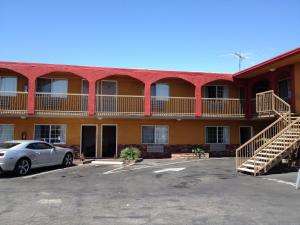 an apartment building with a car parked in a parking lot at Hyde Park Motel in Los Angeles