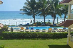 una piscina junto a una playa con palmeras en (J-1) Relaxation on the Beach, en Cabarete