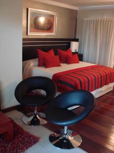 a bedroom with a bed and two black chairs at Zoom Apartments Hotel Boutique in Córdoba