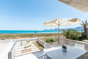ソン・セッラ・デ・マリーナにあるBeach House Pink Rose B in Son Serraのテーブルと椅子、パラソルとビーチが備わります。