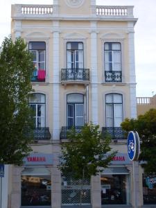 un edificio blanco alto con un reloj en él en Sao Juliao, en Figueira da Foz