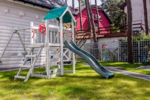 a playground with a slide in a yard at biale domki in Pobierowo
