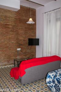 Un dormitorio con una cama con una manta roja. en Apartamentos Fernando El Catolico, en Málaga