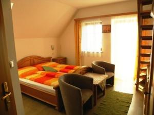 a bedroom with a bed and chairs and a window at Gästehaus Lisa in Deutschlandsberg