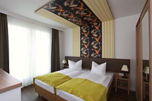 a bedroom with a large bed with a yellow blanket at Hotel Warnow in Rostock