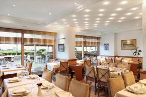 a dining room with tables and chairs and windows at Izmir Palas Hotel in İzmir