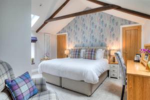 a bedroom with a large white bed and a desk at Bertram's in Warkworth