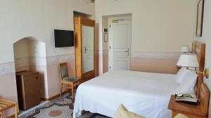 a bedroom with a white bed and a chair at Hotel Roma e Rocca Cavour in Turin