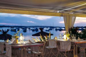 a restaurant with tables and chairs with a view of boats at Hostal la Savina in La Savina