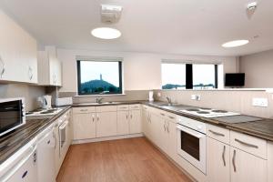 a large kitchen with white cabinets and two windows at Juniper Court in Stirling
