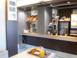 a bakery counter with a plate of pastries and orange juice at B&B HOTEL Tours Nord 1 Val de Loire in Tours