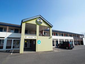 un bâtiment avec une voiture garée sur un parking dans l'établissement B&B HOTEL Tours Nord 1 Val de Loire, à Tours