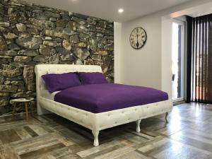 a bed in a room with a stone wall at Apartment Ajla in Tuzla