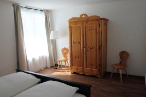 a bedroom with a wooden cabinet and two chairs at Apartments N°7 in Ortisei