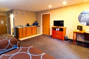 a room with a bed and a kitchen with a television at Super 8 by Wyndham Adrian in Adrian