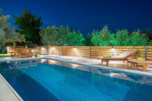 - une piscine avec 2 chaises et une clôture en bois dans l'établissement Natura Verde Villas, à Fiolítis