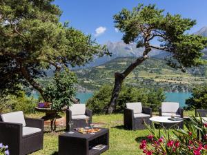 d'une terrasse avec des chaises et des tables et une vue sur le lac. dans l'établissement Logis Hotel Eden Lac, à Savines