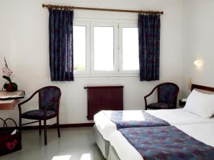 a bedroom with a bed and two chairs and a window at Logis Hotel Eden Lac in Savines