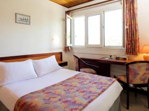 sypialnia z łóżkiem, biurkiem i oknem w obiekcie Logis Hotel Eden Lac w mieście Savines