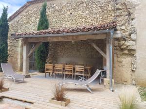 eine Terrasse mit einem Tisch und Stühlen vor einem Gebäude in der Unterkunft Gite de la Commanderie in Castéra-Verduzan