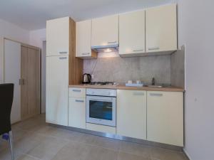 uma cozinha com armários brancos e um fogão em Apartments Goldy em Crikvenica